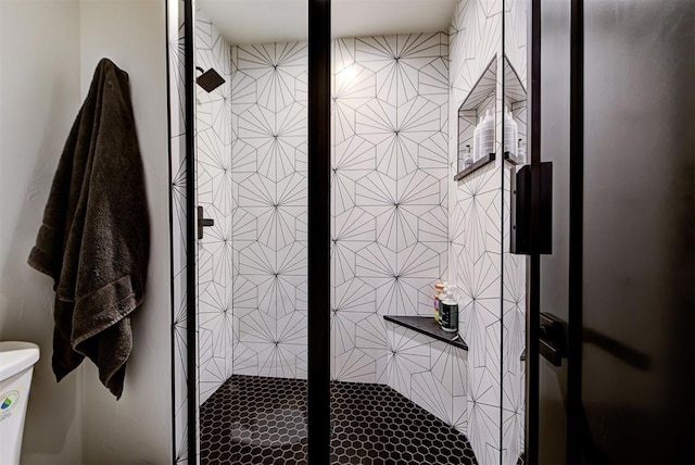 bathroom featuring toilet and a shower with shower door