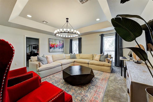 living room featuring a chandelier, light colored carpet, and a raised ceiling