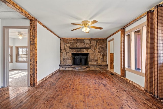 unfurnished living room with wood-type flooring, a stone fireplace, and ceiling fan