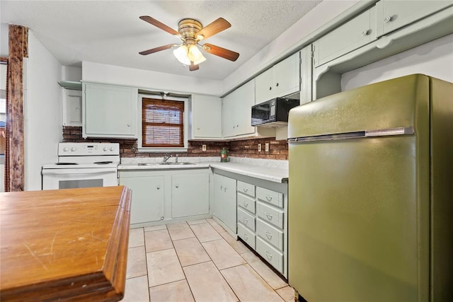 kitchen featuring light tile patterned flooring, white electric stove, fridge, ceiling fan, and a textured ceiling