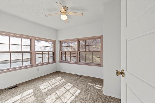 carpeted spare room featuring ceiling fan and a textured ceiling