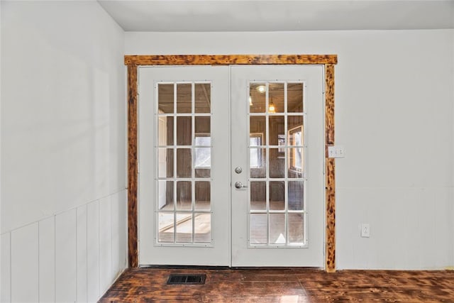 entryway featuring dark hardwood / wood-style floors, wooden walls, and french doors