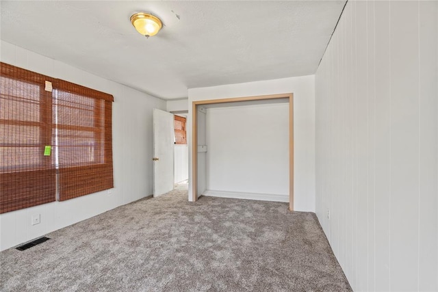 unfurnished bedroom featuring light carpet and a closet