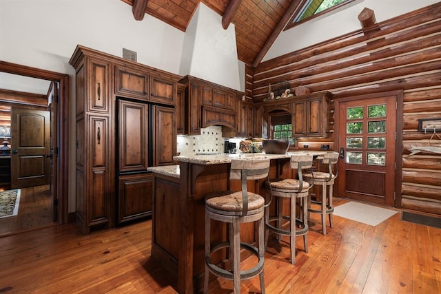 kitchen with hardwood / wood-style flooring, light stone countertops, a kitchen island, and dark brown cabinets