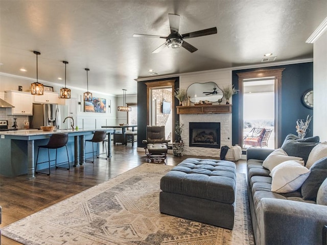 living room featuring a wealth of natural light, dark hardwood / wood-style flooring, ornamental molding, and a fireplace