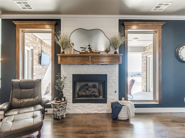 sitting room featuring crown molding, dark hardwood / wood-style floors, and a stone fireplace