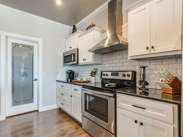 kitchen featuring white cabinetry, decorative backsplash, wall chimney range hood, and appliances with stainless steel finishes