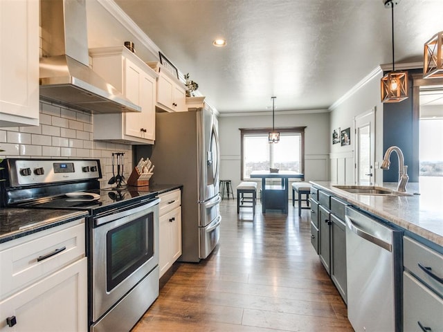 kitchen with pendant lighting, white cabinetry, stainless steel appliances, and exhaust hood