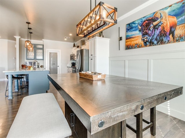 dining space with sink, dark hardwood / wood-style flooring, and ornamental molding