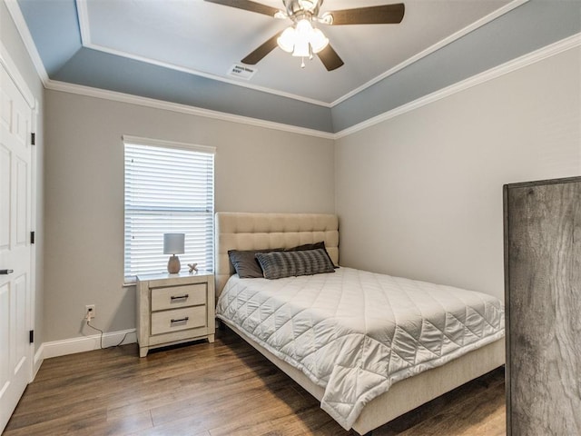 bedroom with ceiling fan, ornamental molding, hardwood / wood-style floors, and a tray ceiling