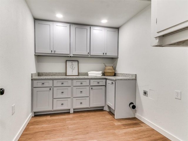 washroom with hookup for an electric dryer, cabinets, and light wood-type flooring