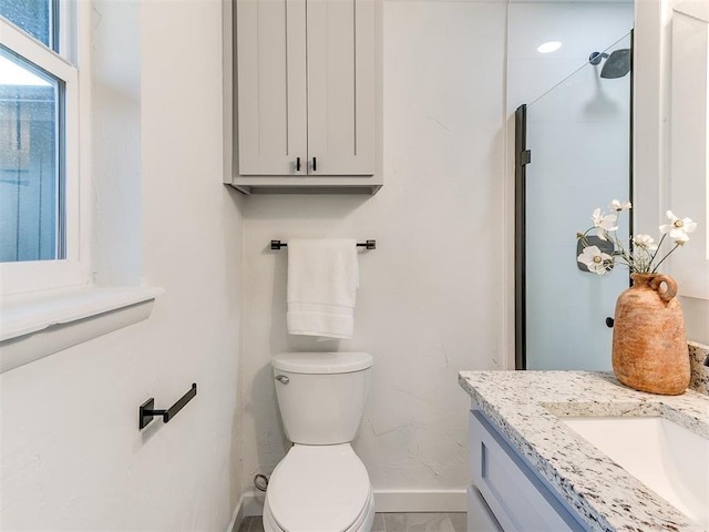 bathroom featuring vanity, walk in shower, and toilet