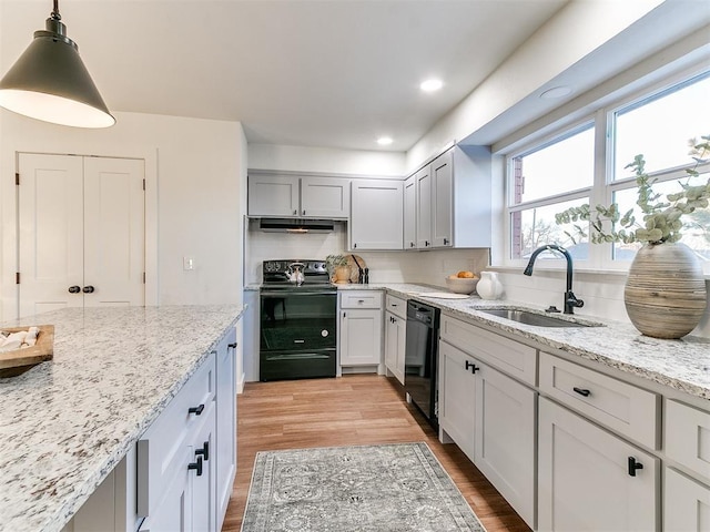 kitchen with sink, light stone counters, black appliances, pendant lighting, and backsplash