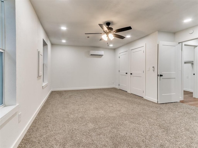 unfurnished bedroom with carpet floors, a wall mounted air conditioner, and ceiling fan