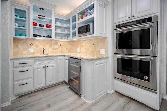 kitchen featuring wine cooler, backsplash, white cabinets, light stone countertops, and stainless steel appliances