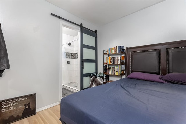 bedroom featuring hardwood / wood-style floors, ensuite bath, and a barn door