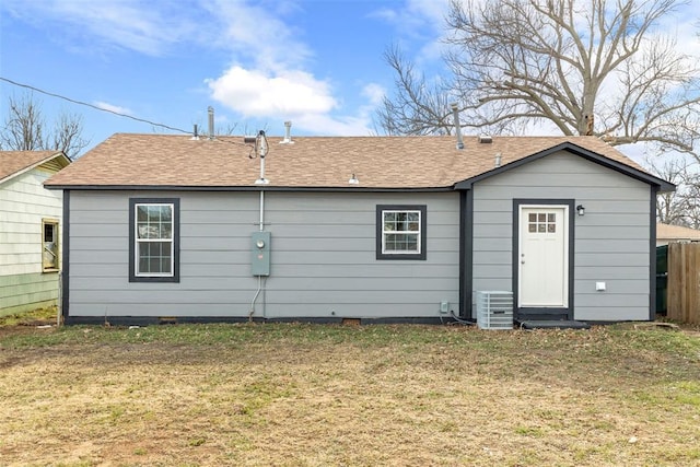 rear view of property featuring cooling unit and a lawn