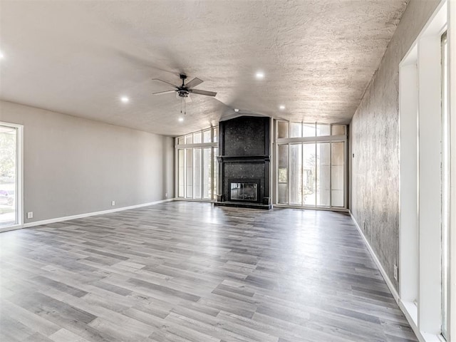 unfurnished living room featuring ceiling fan, a large fireplace, and light hardwood / wood-style flooring