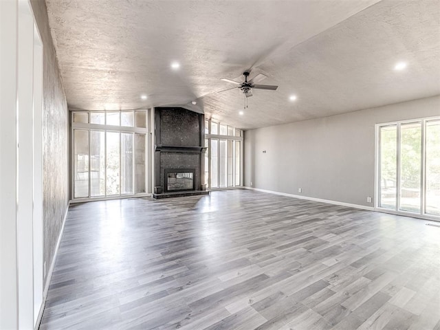 unfurnished living room featuring ceiling fan, a fireplace, and light hardwood / wood-style flooring