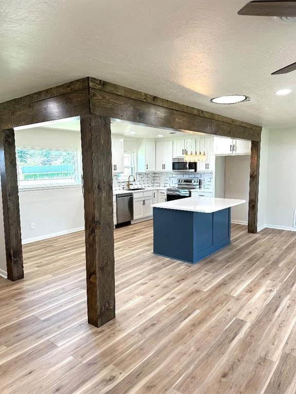 kitchen with white cabinets, stainless steel appliances, decorative backsplash, sink, and light hardwood / wood-style floors