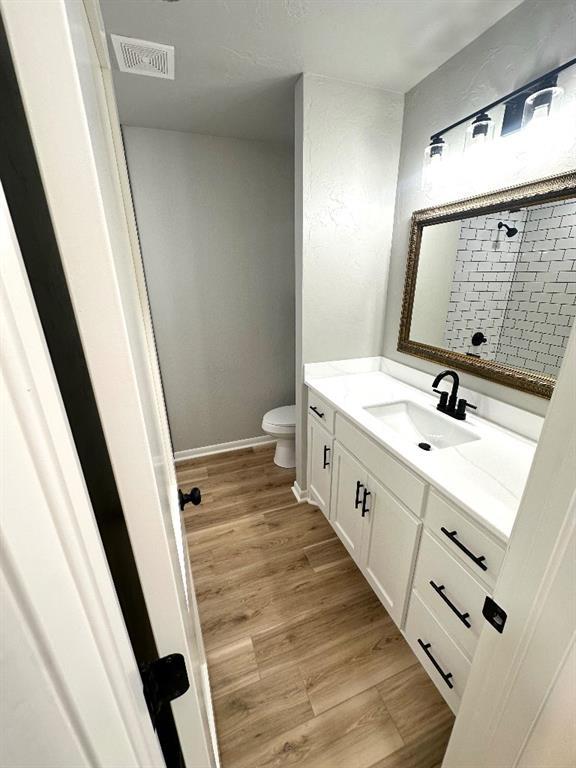 bathroom featuring a shower, wood-type flooring, toilet, and vanity