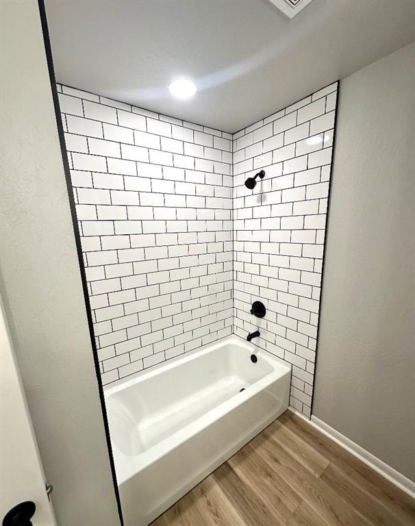 bathroom with hardwood / wood-style floors and tiled shower / bath