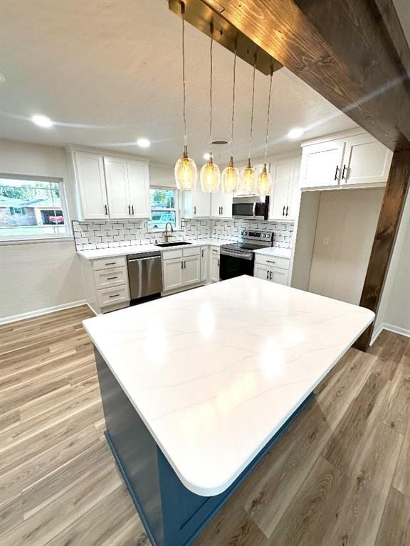 kitchen with white cabinets, backsplash, stainless steel appliances, and pendant lighting