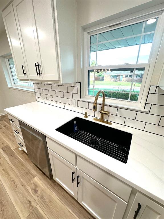 kitchen featuring light wood-type flooring, dishwasher, sink, and white cabinetry