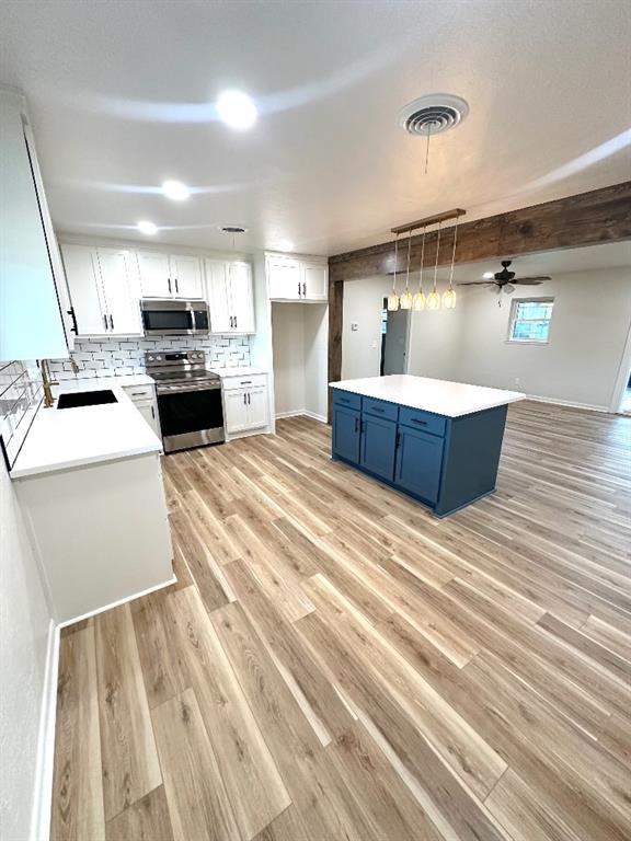 kitchen with tasteful backsplash, sink, appliances with stainless steel finishes, white cabinets, and blue cabinets