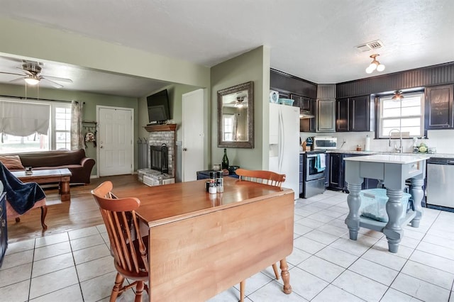 1815 N Bell Ave, Shawnee, OK 74804 - dining space featuring ceiling fan, light tile patterned floors, a fireplace, and plenty of natural light