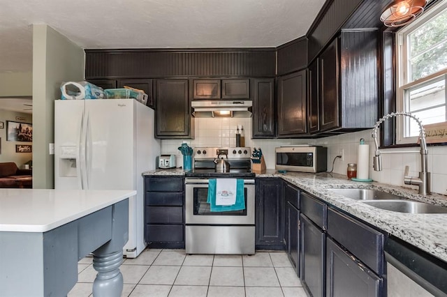 1815 N Bell Ave, Shawnee, OK 74804 - kitchen with appliances with stainless steel finishes, a sink, under cabinet range hood, light tile patterned flooring, and light countertops