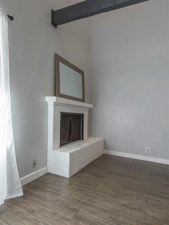 unfurnished living room featuring a brick fireplace and dark wood-type flooring