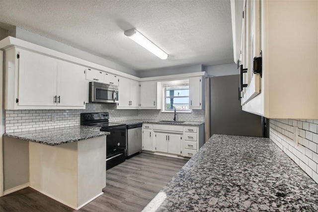 kitchen with sink, white cabinets, stainless steel appliances, and dark stone countertops