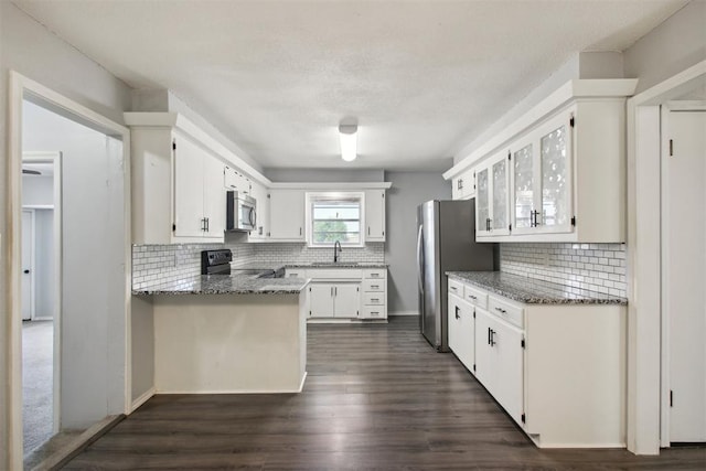 kitchen with white cabinets, stainless steel appliances, dark stone countertops, decorative backsplash, and sink