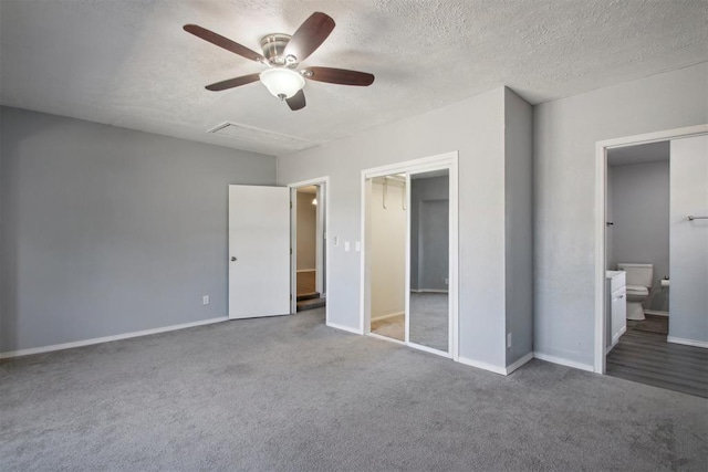 unfurnished bedroom with ceiling fan, carpet floors, ensuite bath, a textured ceiling, and a closet