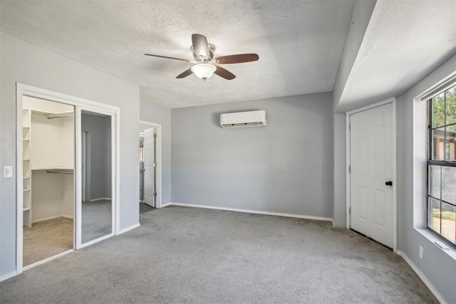 unfurnished bedroom with a wall unit AC, ceiling fan, carpet flooring, and a textured ceiling