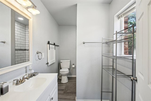 bathroom with hardwood / wood-style flooring, toilet, and vanity