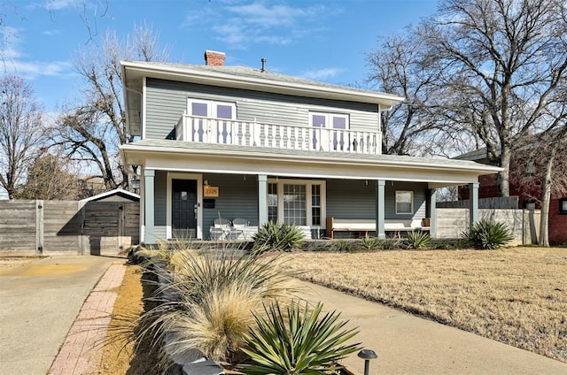 view of front facade with a balcony, a front lawn, and covered porch