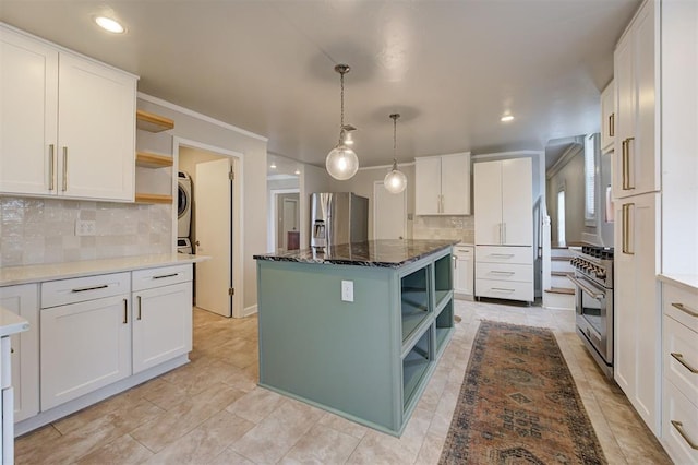 kitchen featuring stacked washer / drying machine, a center island, stainless steel appliances, white cabinets, and dark stone counters