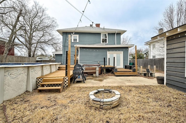 rear view of house featuring a pool with hot tub and a fire pit