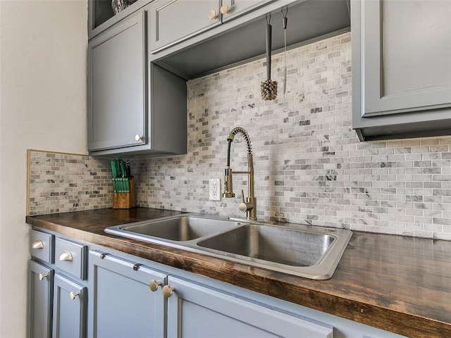 kitchen featuring sink, gray cabinetry, tasteful backsplash, and wood counters