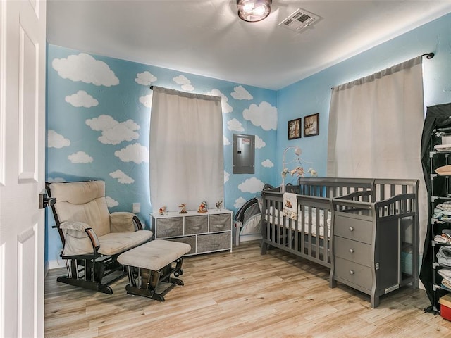 bedroom with light hardwood / wood-style flooring and a crib