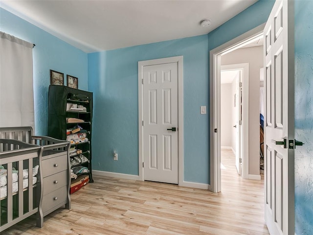 bedroom featuring a crib and light hardwood / wood-style flooring