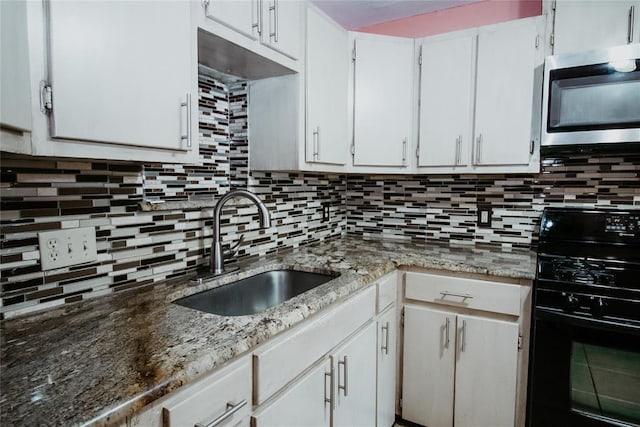 kitchen with backsplash, stone counters, black gas range, sink, and white cabinetry