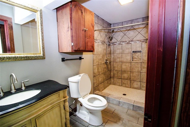 bathroom with toilet, vanity, and a tile shower