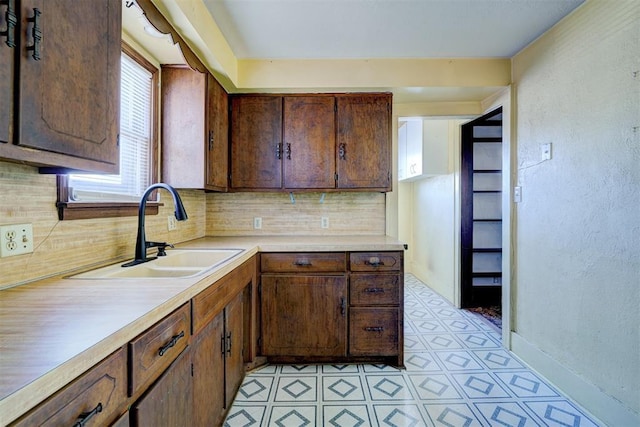 kitchen with tasteful backsplash, dark brown cabinets, and sink