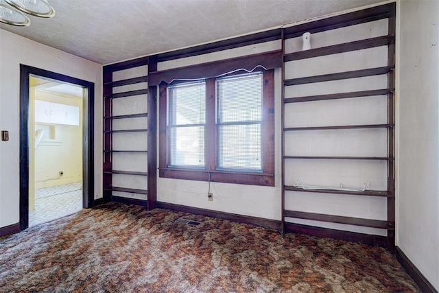 carpeted empty room featuring a textured ceiling