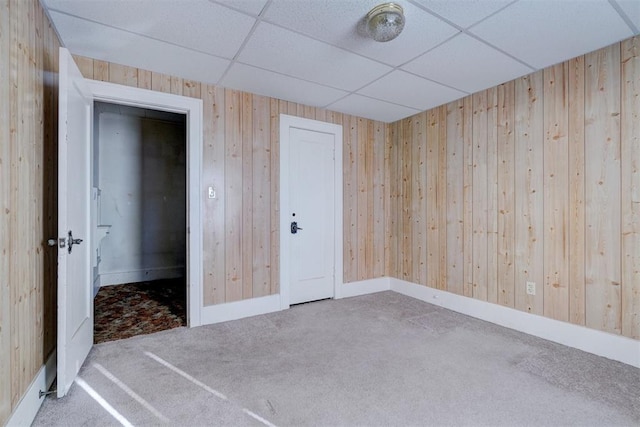 empty room with a drop ceiling and carpet flooring