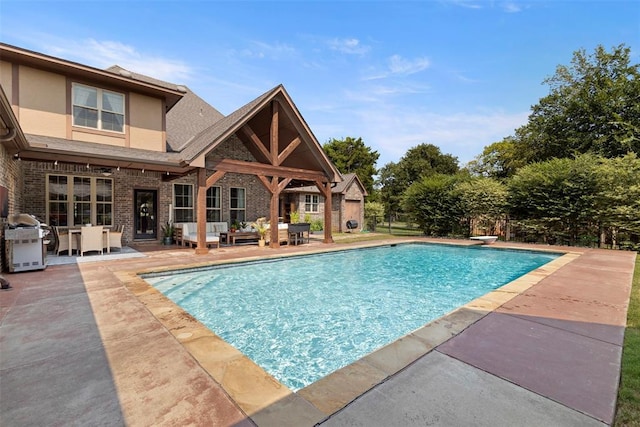 view of swimming pool with area for grilling, a diving board, and a patio area