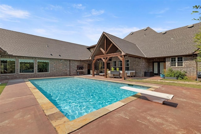 view of swimming pool featuring a patio area and a diving board